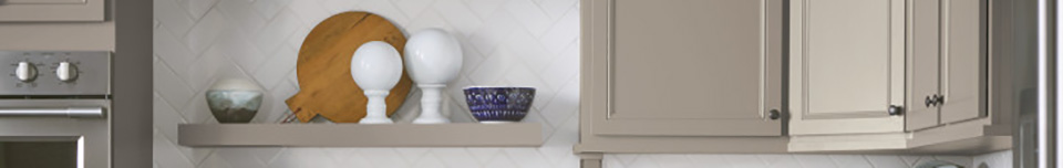 transitional cabinets in light gray with floating shelf and artistic bowls and accent pieces