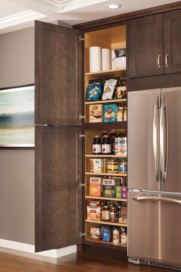 tall pantry cabinet open and full besides closed fridge